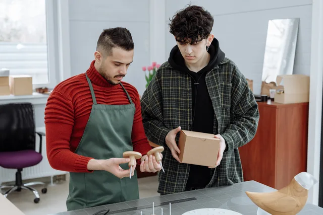 Two men reviewing packaging and craft items in a workshop setting. Collaboration and teamwork. How should an England buyer compare packaging marketing best providers?